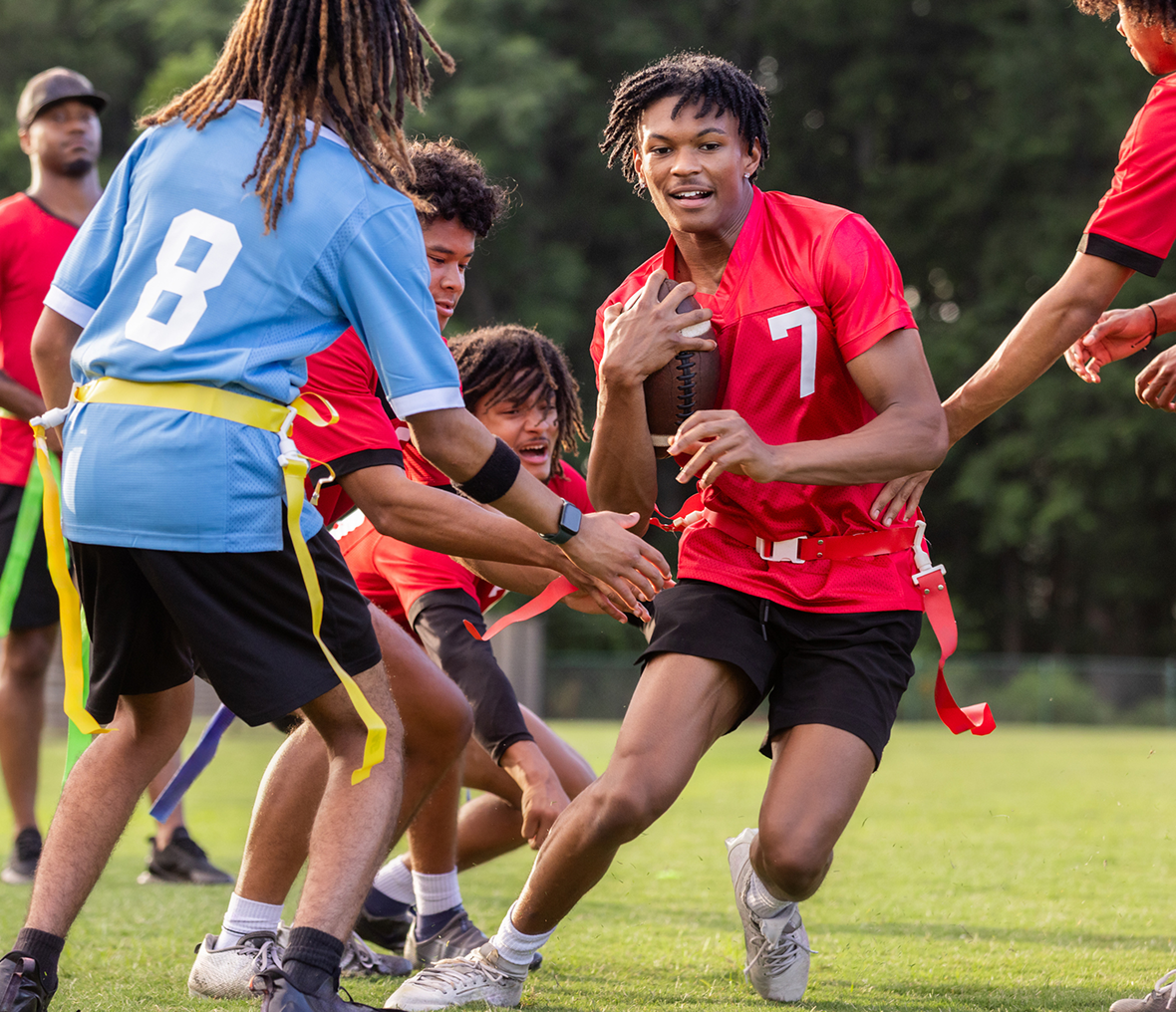 Flag football player wearing red jersey evades defenders